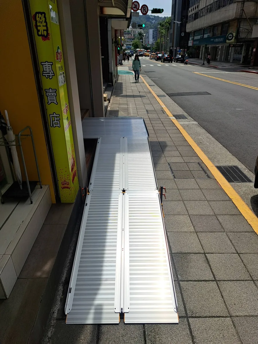 店面人行道輪椅斜坡板無障礙通行 輪椅斜坡板設置於店面入口與人行道之間,改善高低落差。